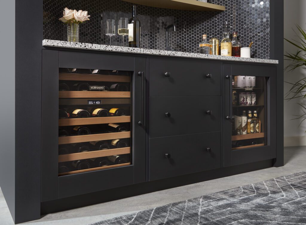 An elegant kitchen featuring Sub-Zero wine storage with black cabinetry and decorative backsplash.